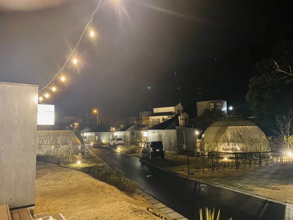 夜のキャンプ施設にランプに照らされたドームテントが立ち並ぶ写真