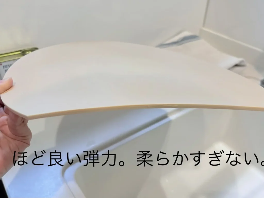 エラストマーのまな板を片手で持ち上げ、僅かにしなる様子を真横から撮影した写真