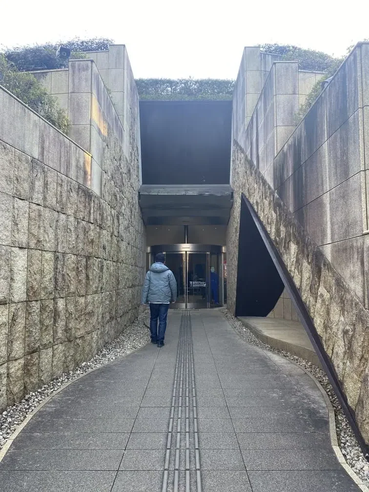 秘密基地のように石壁の間の通路を入っていく作りの岡本太郎美術館の入り口の写真